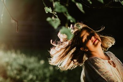 Portrait of woman with tousled hair at park during sunset