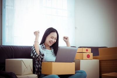 Young woman using phone while sitting on sofa at home