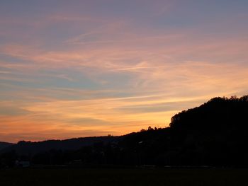 Silhouette trees on field against romantic sky at sunset