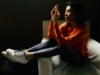 Young woman looking away while sitting at home