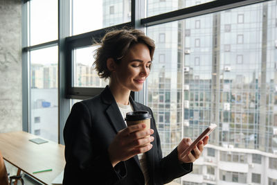 Young woman using mobile phone while sitting at office