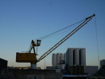 Low angle view of crane against clear blue sky