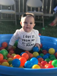 Girl playing with ball while sitting in wading pool