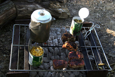 High angle view of meat and cans on barbecue grill