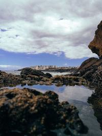 Rock formation on beach against sky