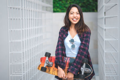 Portrait of smiling young woman standing against wall