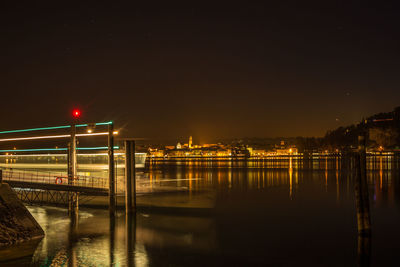 Illuminated bridge over river at night