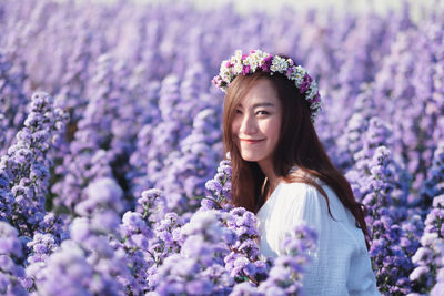 Portrait of smiling woman standing against purple flowering plants