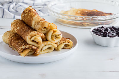 A pile of freshly made rolled crepes served with sweet blueberry sauce.