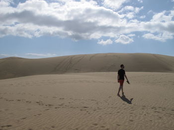 Rear view of man on sand at beach against sky