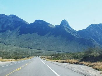 Road by mountains against clear sky