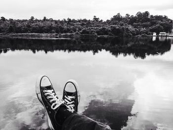 Low section of man standing by lake against sky