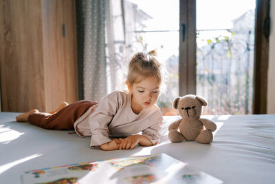 Portrait of cute girl playing with stuffed toy at home