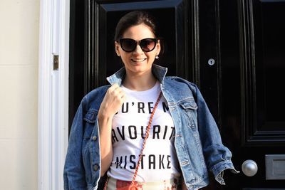 Portrait of smiling woman standing against door