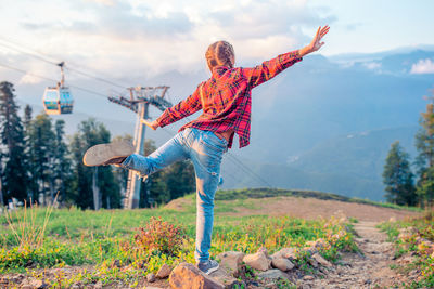 Woman with arms outstretched on mountain against sky