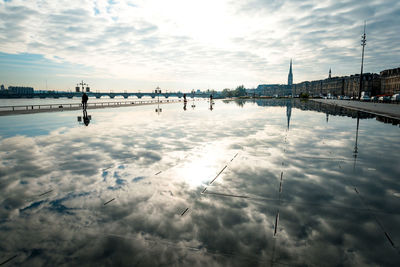 Clouds reflecting on calm lake in city