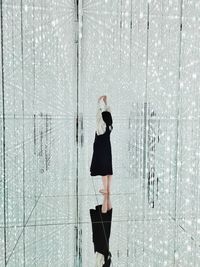Side view of woman standing by glass wall
