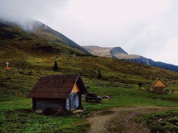 House on field by mountain against sky