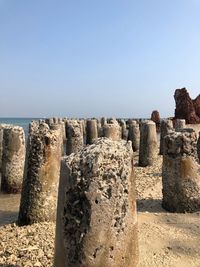 Stone wall by sea against clear sky