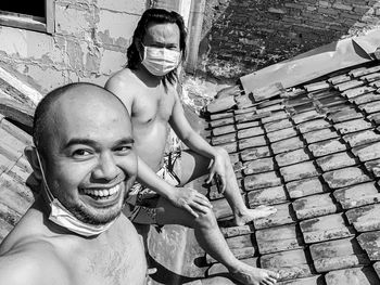 Portrait of two young asian man sunbathing at the roof wearing mask in quarantine periode