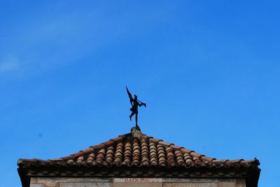 Low angle view of weather vane against blue sky