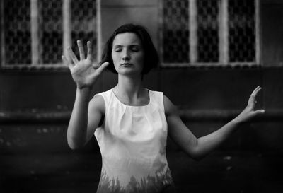 Young woman with eyes closed standing against building