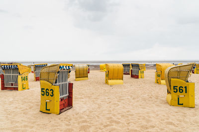 Hooded chairs on beach against sky