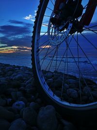 Close-up of bicycle wheel on rocks by sea