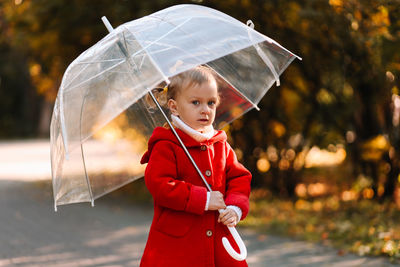 Cute girl holding umbrella while standing outdoors