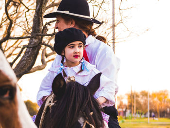 Mother and daughter riding horse at park