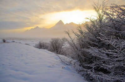 Scenic view of snow covered mountains against sky at sunset