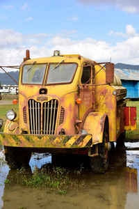 Abandoned truck by water against sky