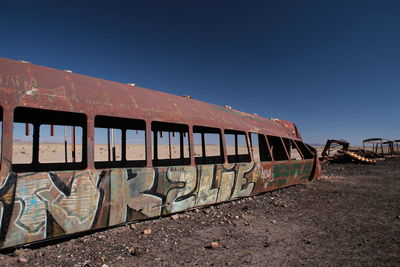 Graffiti on abandoned train against clear blue sky