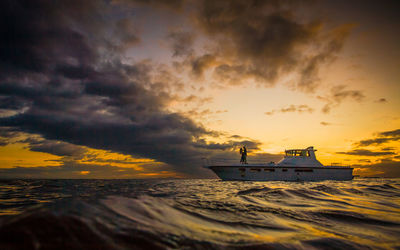 Silhouette of boat sailing on sea during sunset