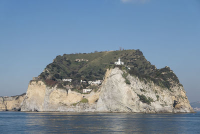 Rock formations by sea against clear blue sky