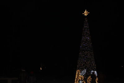 Low angle view of illuminated christmas tree against sky at night