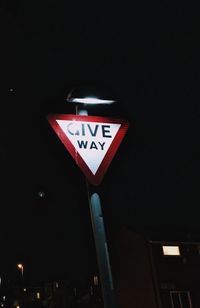 Low angle view of road sign at night