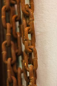 Close-up of rusty chains against white wall