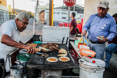 Man and fish on barbecue grill at market stall