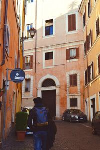 Rear view of man in front of residential buildings