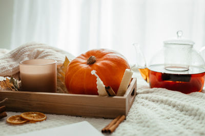 Autumn cozy composition. autumn decoration of pumpkin, candles and fallen leaves next to a kettle
