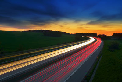 Light trails on road against sky at sunset