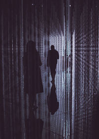 Rear view of silhouette man and woman standing against curtain