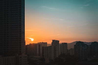 Buildings in city against sky during sunset