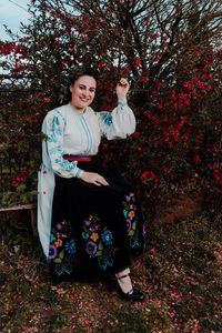Portrait of smiling young woman standing against trees