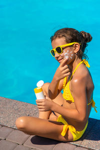 Portrait of young woman drinking water in swimming pool
