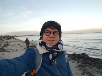 Portrait of mature man at beach against sky
