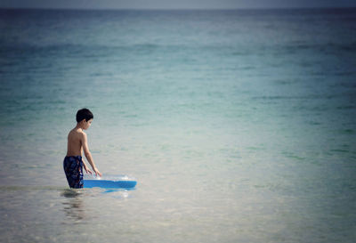 Shirtless boy with inflatable ring in sea