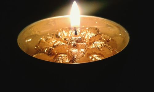 Close-up of lit candle against black background