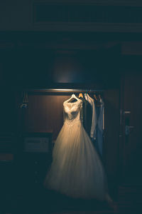 Wedding dress hanging in closet in darkroom